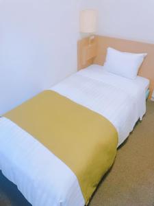 Una gran cama blanca con una manta amarilla. en Fuchu Urban Hotel en Fuchu
