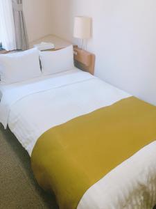 府中市にある府中アーバンホテルの大型ベッド(黄色と白の毛布付)