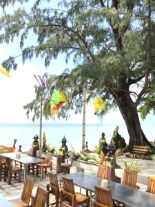 a restaurant with tables and chairs on the beach at Andaman Beach Resort Koh Jum in Ko Jum
