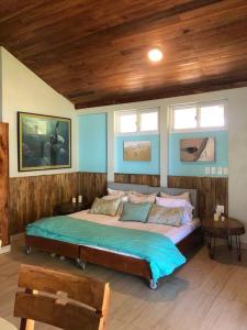 a bedroom with a bed with blue walls and windows at Turtles Nest Bunkhouse at Lodge at Long Bay in Corn Island