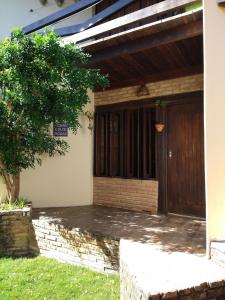 Apartamento/Duplex Praia do Francês في برايا دو فرانسيس: بيت فيه باب خشبي وشجر