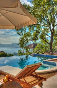 a pool with a chair and an umbrella at Harmonia Bungalows & Pool in Sveti Stefan