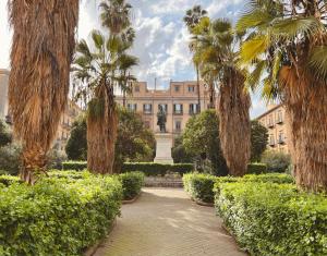 a garden with palm trees and a building at Archè Design Rooms and Suites in Palermo