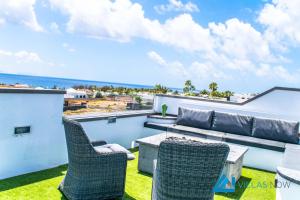 een terras met een bank en stoelen op een dak bij Villa Graciosa By Villas Now Ltd in Playa Blanca