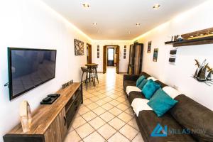 een woonkamer met een bank en een flatscreen-tv bij Villa Graciosa By Villas Now Ltd in Playa Blanca