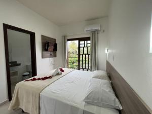 a bedroom with a large white bed with red flowers on it at Pousada Battistella in Garopaba +35 photos