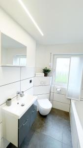 La salle de bains blanche est pourvue de toilettes et d'un lavabo. dans l'établissement Uraha Apartments Seukendorf, à Seukendorf