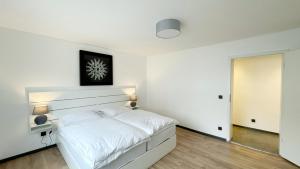 a white bedroom with a white bed and a door at Uraha Apartments Seukendorf in Seukendorf