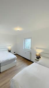 a white bedroom with two beds and a window at Uraha Apartments Seukendorf in Seukendorf