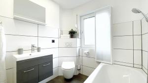 La salle de bains blanche est pourvue d'un lavabo et de toilettes. dans l'établissement Uraha Apartments Seukendorf, à Seukendorf