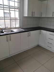 a kitchen with white cabinets and a sink at Lisokhanya GuestHouse in East London