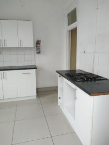 a kitchen with white cabinets and a black counter top at Lisokhanya GuestHouse in East London