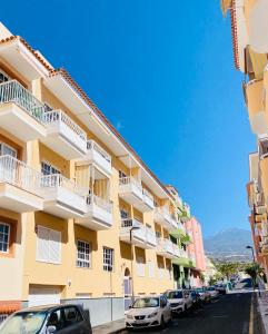 a row of buildings on a street with parked cars at Casa del Sol - with Home Office space in Playa de San Juan