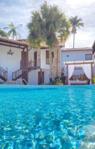 a villa with a swimming pool in front of a house at Pousada Valhacouto in Paraty