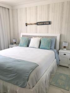 a bedroom with a large white bed with blue pillows at Apt Coral Azul Iberostate Praia do Forte in Praia do Forte