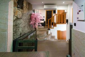 ein Zimmer mit einer Steinmauer und einer Vase mit rosa Blumen in der Unterkunft Casa da Fonte in Campo do Gerês