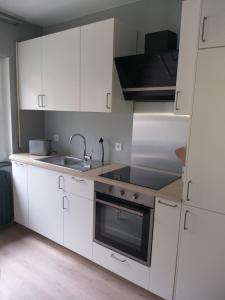 uma cozinha com armários brancos e um lavatório em La Maison de Sidonie em Jalhay