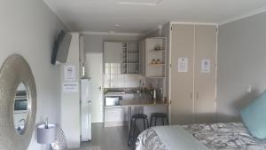 um quarto com uma cama e uma cozinha com armários brancos em THE SPARE BEDROOM Unit 2 em Harrismith
