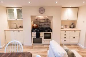 cocina con fogones y sofá en una habitación en The Snug, en Great Malvern 15 fotos más