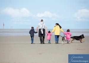een familie die op het strand loopt met hun hond bij Friesenhain Ferienwohnungen in Sankt Peter-Ording
