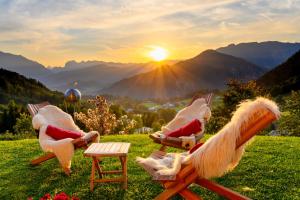 a group of chairs sitting in a field with the sunset at Alpenhotel Denninglehen in Berchtesgaden