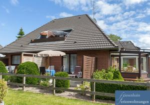 a house with a fence and an umbrella at Friesenhain Ferienwohnungen in Sankt Peter-Ording