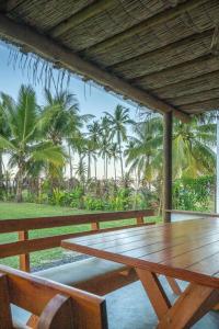 una mesa de madera y sillas en una terraza con palmeras en Welove Beach House-Pés na areia Quintal dos Sonhos, en Serra Grande