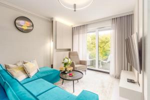 a living room with a blue couch and a table at Apartamenty Fenomen - Premium Park & Sea, Nadmorskie Tarasy FREE PARKING, SWIMMING POOL, SAUNA AND OTHER! in Kołobrzeg