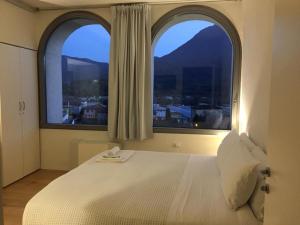 una camera da letto con due grandi finestre e un letto bianco di La Ripa Boutique Hotel ad Albino