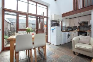 eine Küche mit einem Holztisch und weißen Geräten in der Unterkunft Swift Cottage in Broadhempston