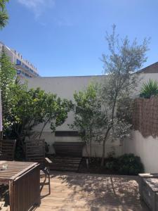 eine Terrasse mit Stühlen, Bäumen und einer Wand in der Unterkunft Garden Apartment in Lissabon