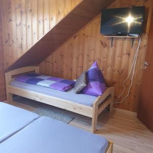 ein kleines Bett in einem Holzzimmer mit einem TV in der Unterkunft Ferienwohnung Sirch in Diedorf