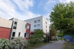 ein weißes Gebäude neben einer Straße mit Bäumen in der Unterkunft Akademiehotel Jena in Jena