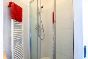 La salle de bains est pourvue d'une douche avec une porte en verre. dans l'établissement La Station - Lourdes - Centre - Residence Serenity, à Lourdes