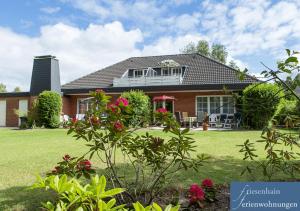a house with a green yard with flowers at Friesenhain Ferienwohnungen in Sankt Peter-Ording