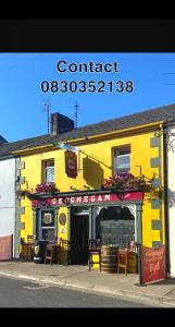 a yellow building with a sign that reads contact overseas at Geoghegans Magpie Bar and B&B in Glin