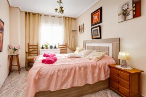 a bedroom with a large bed with pink stuffed animals on it at Apartament Caballero de Rodas in Torrevieja