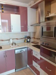 una cocina con armarios rojos y electrodomésticos de acero inoxidable en Albaida II Bajo G Apartamento Nerja, en Nerja