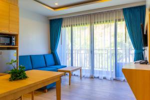 a living room with a blue couch and a large window at Golden Paradise Hotel - SHA PLUS in Karon Beach