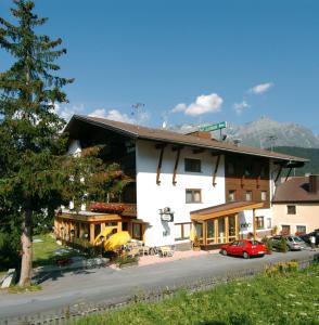 un gran edificio blanco con coches estacionados frente a él en Hotel Garni Lamm, en Nauders