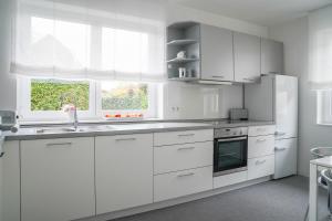 a white kitchen with white cabinets and a refrigerator at Modernes Stadthaus | Parkplatz | WiFi | Bad&Dusche | Küche in Hannover