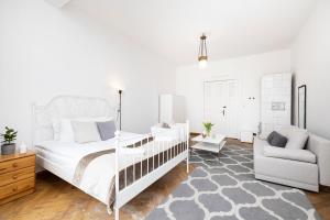 a white bedroom with a bed and a chair at Baltic Rooms Sopot in Sopot