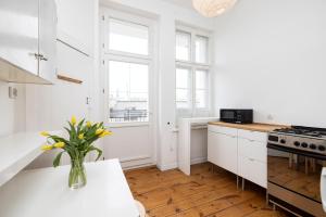 a white kitchen with a vase of flowers on a counter at Baltic Rooms Sopot in Sopot