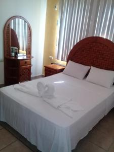 een bed met witte lakens en een strik erop bij DON CELES in Paraíso
