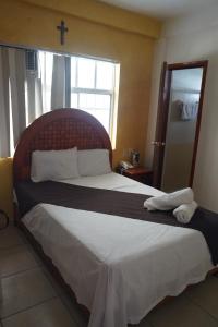 a bedroom with a large bed with a cross on the wall at DON CELES in Paraíso