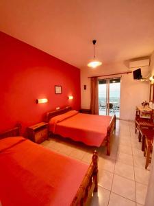 a red bedroom with two beds and a balcony at Stelios Studios in Tragaki