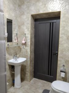ein Bad mit einem Waschbecken, einem WC und einer schwarzen Tür in der Unterkunft Chinara Guest House Airport in Taschkent