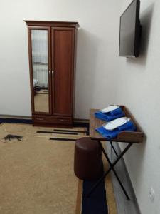 Zimmer mit einem TV und einem Tisch mit Handtüchern. in der Unterkunft Chinara Guest House Airport in Taschkent