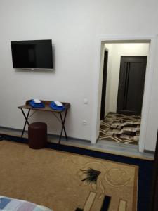 a room with a table and a tv on a wall at Chinara Guest House Airport in Tashkent