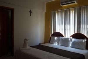 a bedroom with two beds and a cross on the window at DON CELES in Paraíso